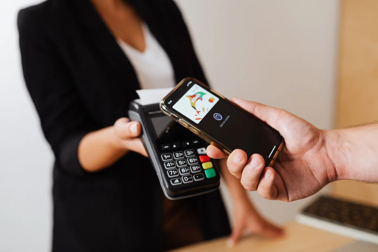 A person paying with a smartphone at a counter