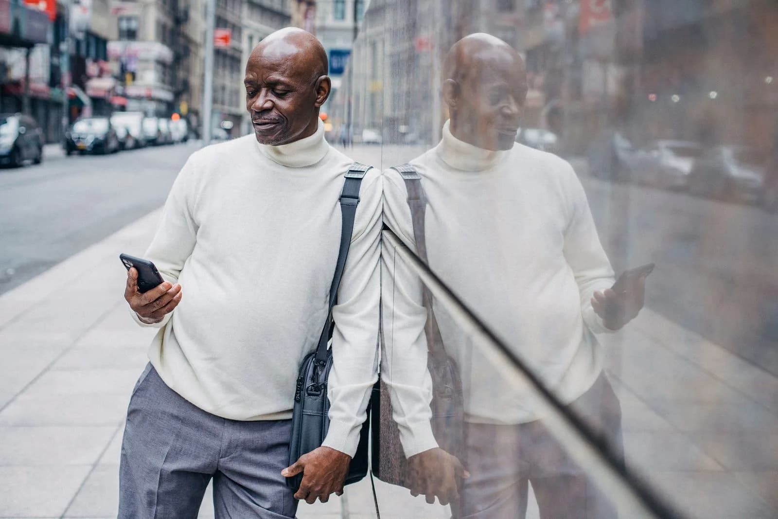 A man in a city street reading something on his phone
