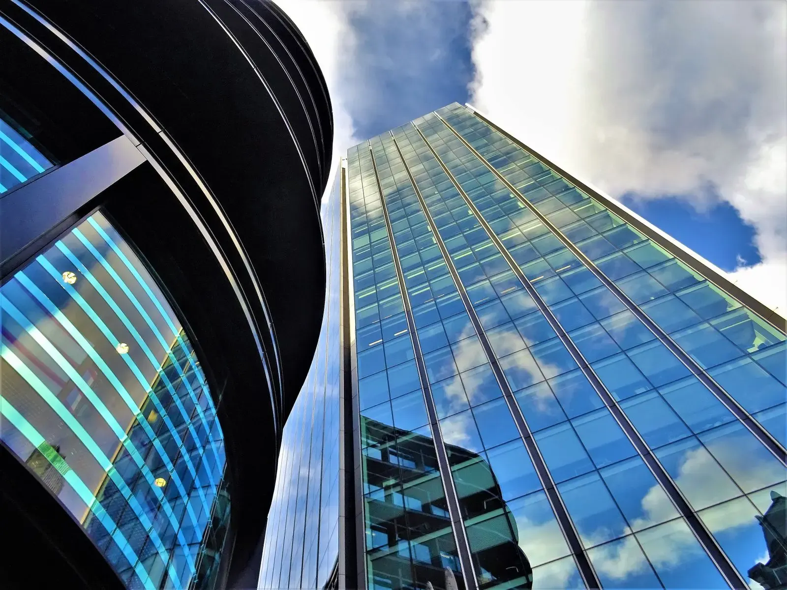 Glass office towers reflecting a cloudy sky